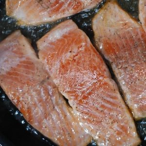Des morceaux de saumon cuisant dans une poêle.