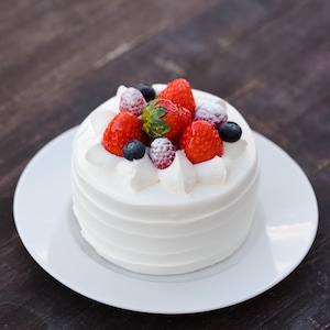 Un petit gâteau recouvert de crémage blanc et de petits fruits.