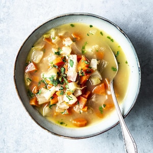 Un bol de soupe aux légumes avec une cuillère.