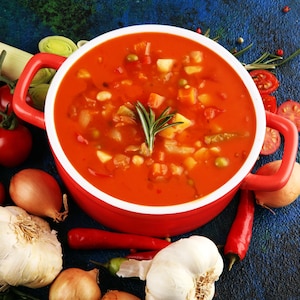 Un bol de soupe minestrone entouré de légumes.