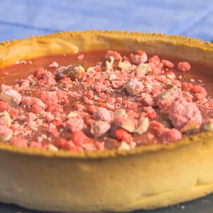 Une tarte vue de près avec de la praline rouge émiettée sur le dessus. 