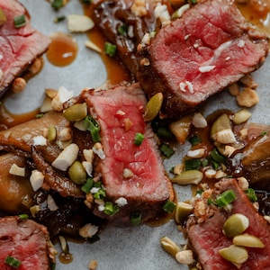 De fines lanières de bison en tataki, nappées de sauce à l'érable et garnies d'un mélange de noix et de fines herbes.