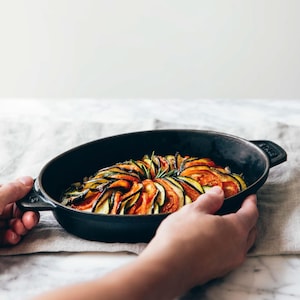 Un tian de légumes rôtis servi dans une poêle en fonte.