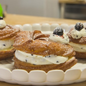 Trois pâtisseries de type choux à la crème disposées dans une assiette de service.