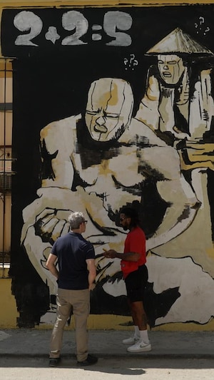 L’artiste cubain Fabián López et le journaliste Yanik Dumont-Baron sont debout devant une murale à La Havane, à Cuba.