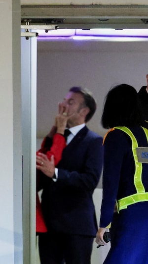La main de Brigitte Macron sur le visage d'Emmanuel Macron, à sa sortie de son avion présidentiel.