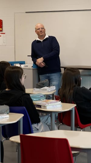 Un professeur est debout à l'avant d'une classe. 
