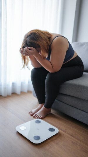 Une femme découragée à côté de sa balance