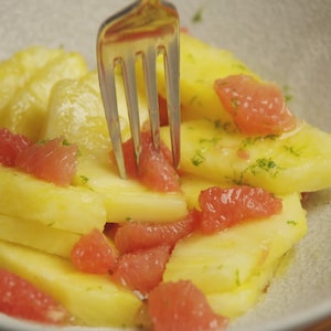 Une salade de fruits d'ananas et de pamplemousses dans un bol blanc.