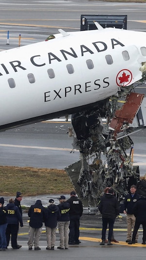 Des agents proches d'un avion dont le poste de pilotage est détruit.