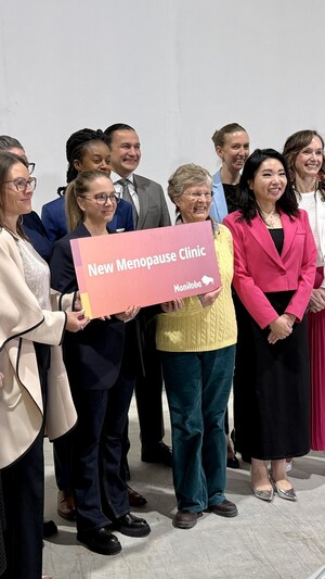 Des personnes tiennent une pancarte avec la mention "New Menopause Clinic" en anglais, et prennent une photo.