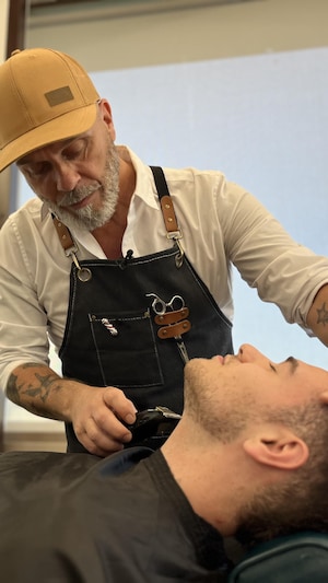 Un homme qui taille la barbe d'un client couché sur une chaise de barbier