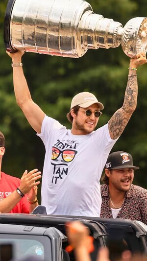 Il est &agrave; l'arri&egrave;re d'un v&eacute;hicule et tient le coupe &agrave; bout de bras.