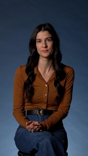 Brigitte est assise dans un studio de Radio-Canada devant un fond bleu uni.