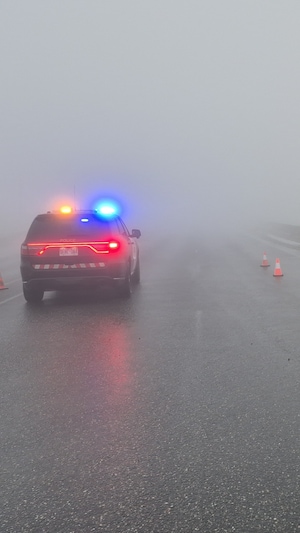 Une autopatrouille de la Police provinciale de l'Ontario et des cônes de circulation dans le brouillard.