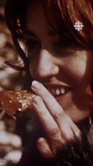 Une femme souriante qui mange de la tire sur la neige.
