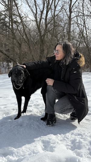 Camille Gallard est assise à côté de Cookie dans la neige. 