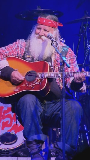 Cayouche avec sa guitare, sur une sc&egrave;ne.