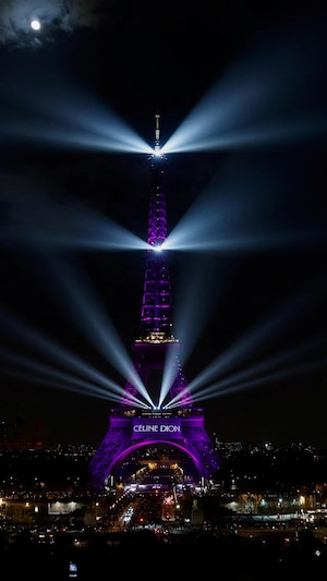 On voit la tour Eiffel illuminée en mauve. Le nom de Céline Dion est aussi affiché. 