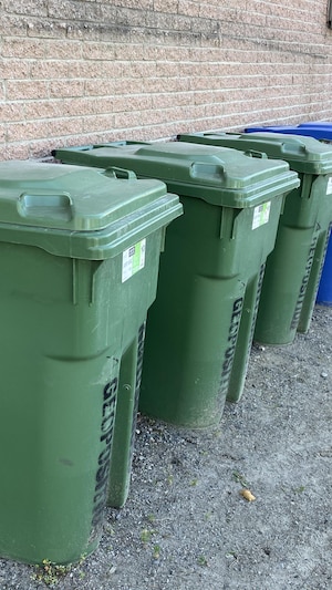 Des bacs de matières résiduelles et de recyclage derrière un bâtiment commercial.