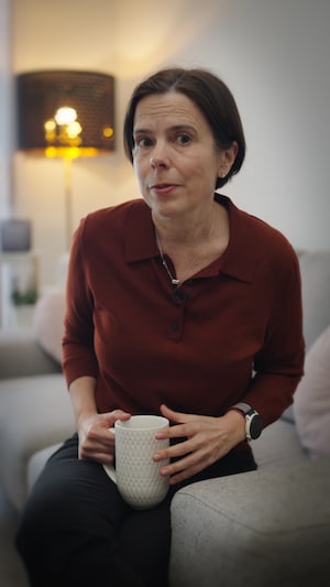 La journaliste Dominique Forget est assise sur un canapé, une tasse à la main.