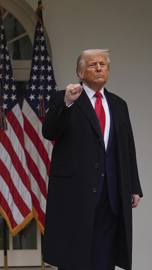 Donald Trump brandit le poing devant une rangée de drapeaux des États-Unis, devant la Maison-Blanche, le 2 avril 2025.