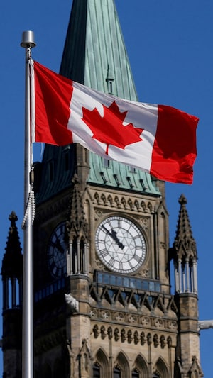 Un drapeau canadien flotte dans les airs sur la colline parlementaire à Ottawa. 