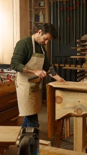 Un ébéniste assemble deux morceaux de bois pour en faire un meuble.