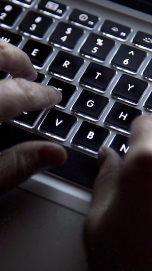 Des mains devant un clavier d'ordinateur.