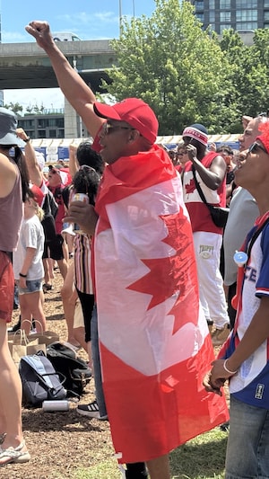 Des partisans habillés de blanc et rouge lèvent le poing en direction d’un écran géant.