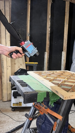 Une personne travaille sur un cadre en bois à l'aide d'un laser.