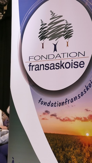 Une banderole de la Fondation fransaskoise avec, à l'arrière-plan, un centre d'appel dans le cadre du Francothon 2024.