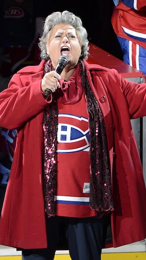 Ginette Reno porte le chandail de l'équipe et chante sur la glace. 