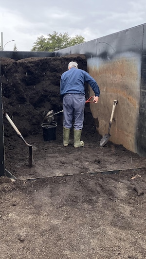 Un homme à l'intérieur d'un conteneur met du compost dans une chaudière à l'aide d'une pelle.