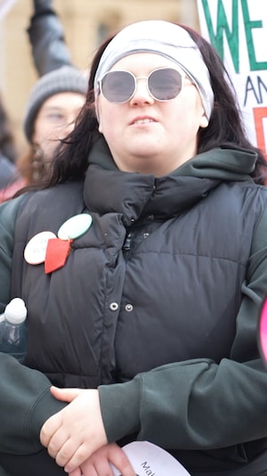 Une personne dans uine manifestation portant un carré rouge.