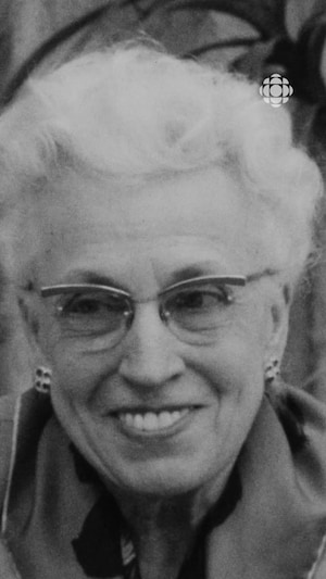 Femme portant des lunettes arborant un sourire taquin.