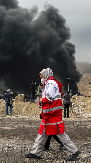 Une femme avec un masque marche entour&eacute;e de nuages noirs.