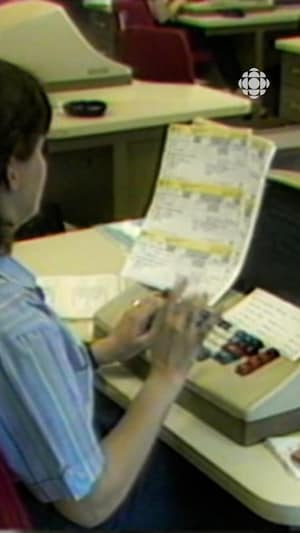 Une femme utilise une machine de saisie de données pour traiter des formulaires fiscaux dans un bureau.