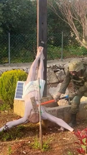 Un soldat détruit une statue de Jésus.