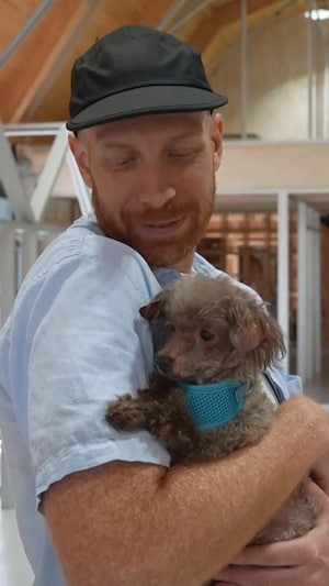 Jean-Philippe tient un chien dans ses bras.