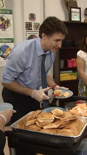 Justin Trudeau donne une assiette de pain et de fromage à une élève.