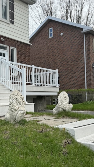 Deux statues de lion ornent l'entrée d'une propriété.