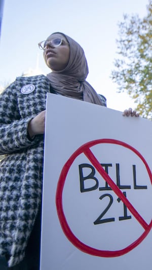 Des militants brandissent des affiches critiquant la Loi sur la laïcité de l'État et qualifiant celle-ci de « xénophobe ».