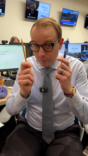 Louis Blouin est assis sur sa chaise de bureau et tient un crayon et un stylo dans ses mains.