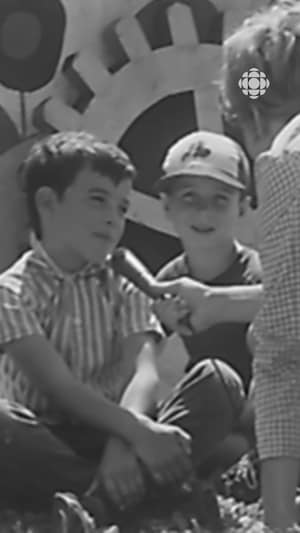 Deux jeunes garçons assis au sol répondent aux questions d'une journaliste qui leur tend un micro.