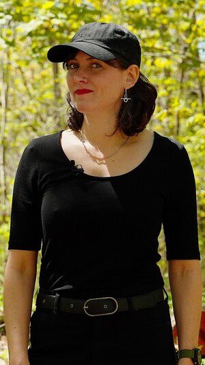 Une femme habillée en noir dans une forêt.