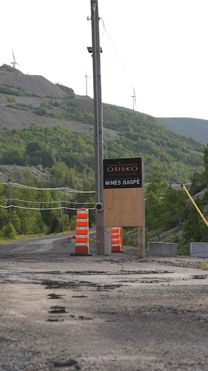 Une affiche de Métaux Osisko devant un chemin menant au site de la mine du mont Copper.