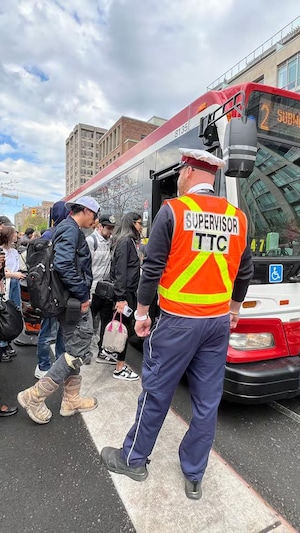 Un superviseur de la CTT regarde des gens entrer dans un autobus.