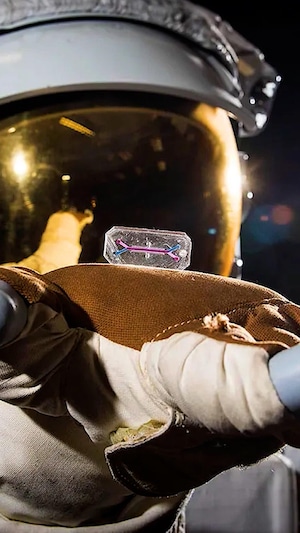 Un astronaute tient une puce électronique dans sa main.