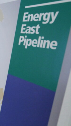 Une panneau illlustre le tracé du projet de pipeline Énergie Est, en arrière-plan, deux dirigeants de la compagnie TransCanada, le promoteur du projet
